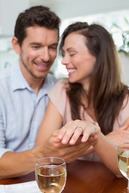 Happy woman showing engagement ring besides man