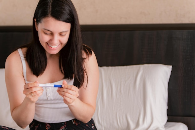 happy woman showing positive pregnancy test close up