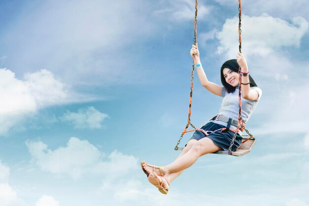 Happy woman sit on swing with blue sky background