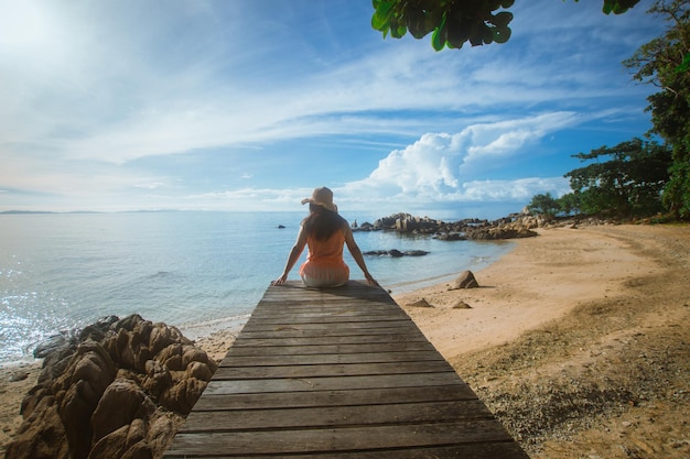 Happy woman sitting on wood bridge with view of the sea soft focus with noise