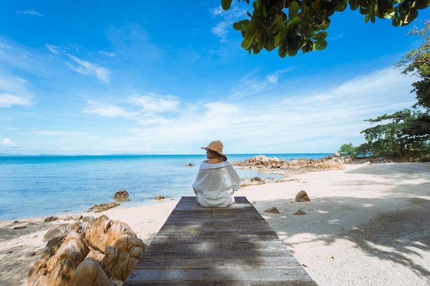 Happy woman sitting on wood bridge with view of the sea soft focus with noise