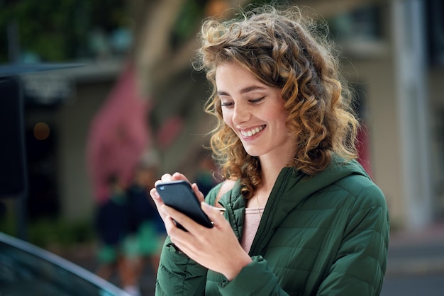 Happy woman smile and typing on phone during travel in city using social media internet and 5g network connection outside Young female flirting on a mobile app for communication on urban street