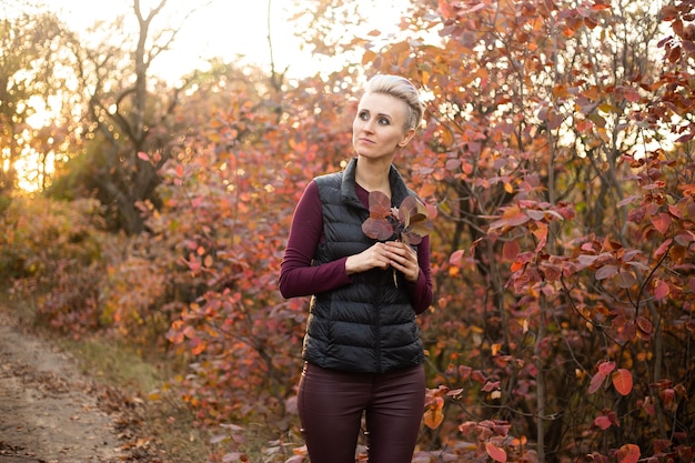 Happy woman smiling and playing with autumn leaves Autumn woman fall