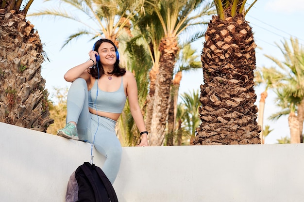 Happy woman in sportswear with a phone listens to music with a headphones