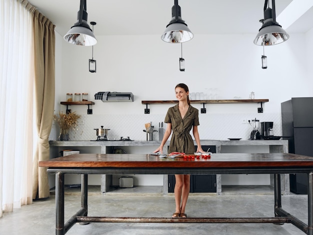 Photo happy woman standing fulllength in stylish minimalist kitchen interior with natural elements in wood