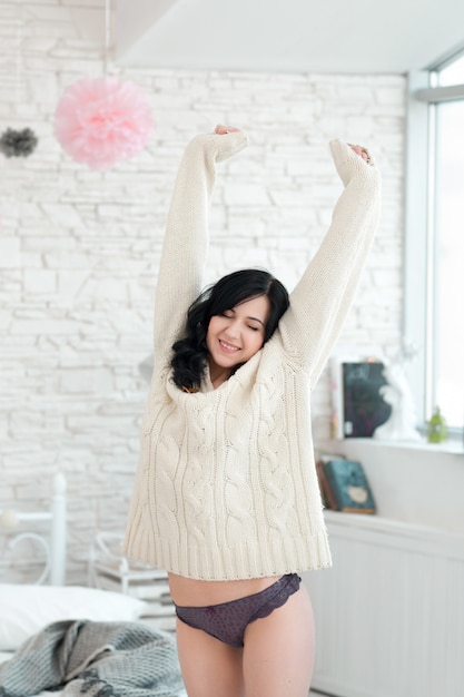 Happy woman stretching in bedroom in the morning