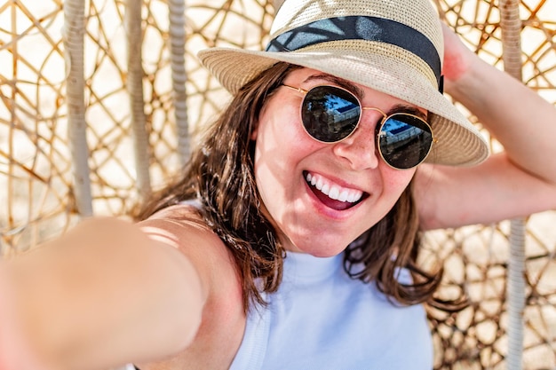 Happy woman taking selfie photo while sitting in summer park