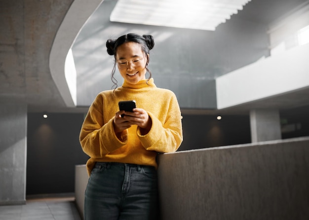 Happy woman and texting on phone in office building relax while on internet search and reading Asian girl and business entrepreneur with smartphone for research office space or idea in Japan