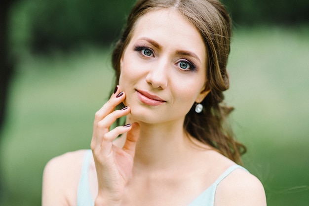 Happy woman in a turquoise long dress in a green park