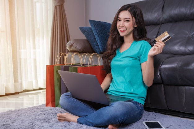 Happy woman using laptop computer for online shopping with credit card in living room