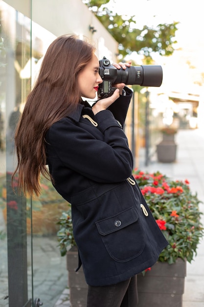 Happy woman on vacation photographing with camera on the city street. Having fun in the city with camera, travel photo of photographer.