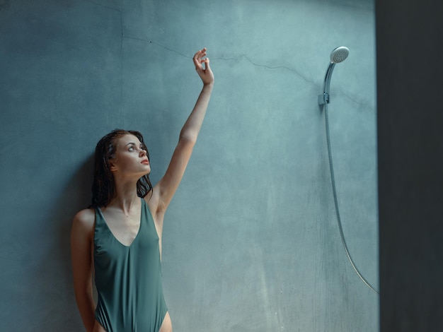 Happy woman in a vibrant green bathing suit celebrating with arms raised by a colorful wall