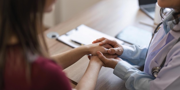 Happy woman visiting doctor senior getting optimistic news after medical checkup therapy Therapist holding hand of patient giving hope support congratulating on goor treatment result