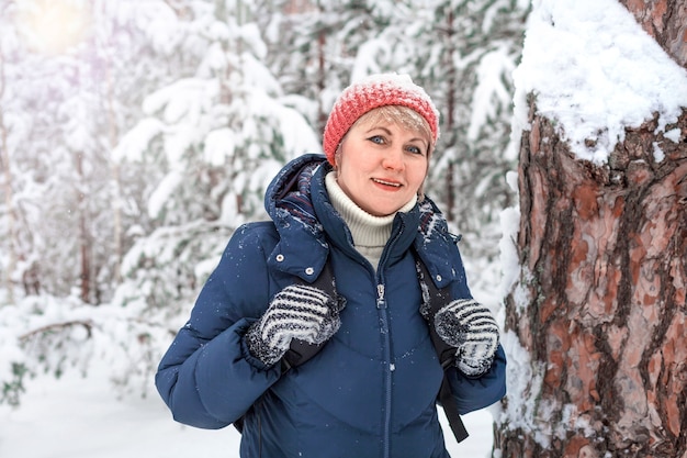 Happy woman walking in winter forest. A middle-aged woman is freezing in the Park.