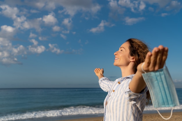 Happy woman wearing medical mask outdoor against blue sky background