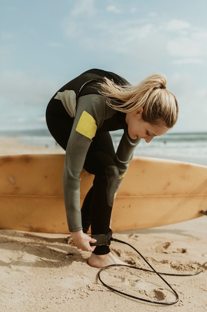 Photo happy woman wearing a surfboard leash