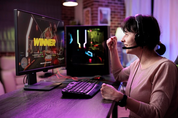 Happy woman winning video games tournament on live stream, using computer to have fun in rpg championship with multiple players. Female gamer celebrating action gameplay challenge win.