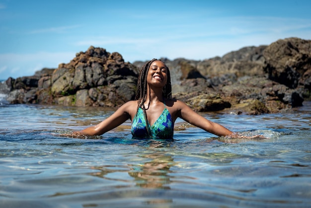 Happy woman with braided hair and a blue dress with her body in the water posing for a photo