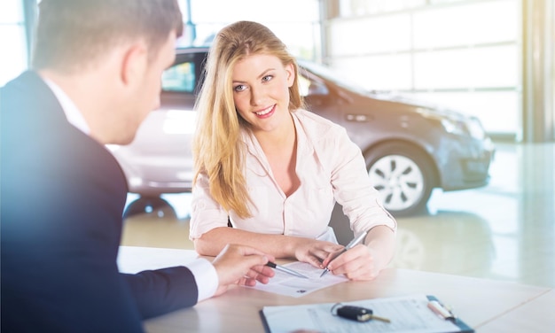 Happy woman with car dealer in auto show or salon