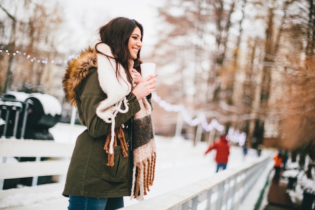 Happy woman with a cup of hot drink on  cold winter outdoors at Christmas market