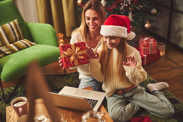 Happy woman with daughter celebrating Christmas with relatives online