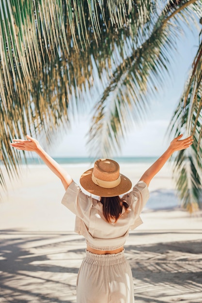 Happy woman with hat relaxing at the seaside and looking away