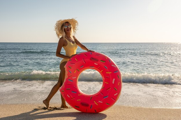 Happy woman with inflatable donut on a tropical beach.