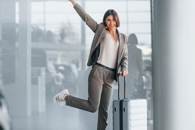 Happy woman with luggage is standing indoors Conception of tourism