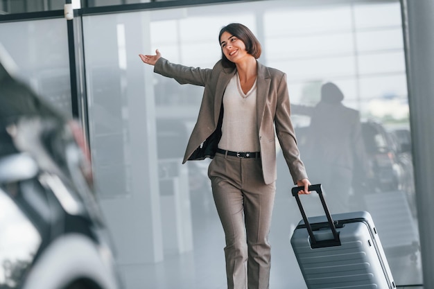 Happy woman with luggage is standing indoors Conception of tourism