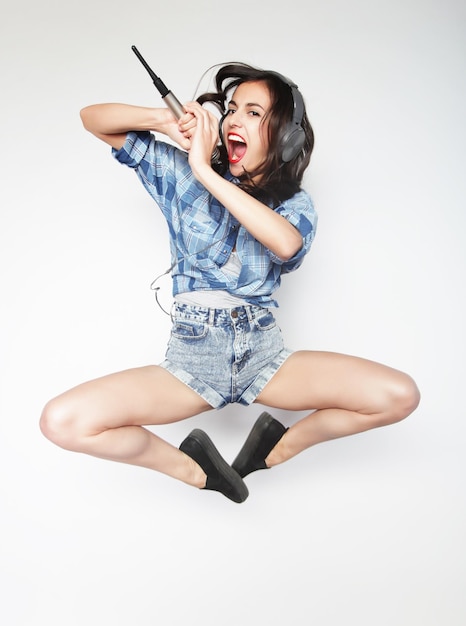 Happy woman with microphone jumping and singing