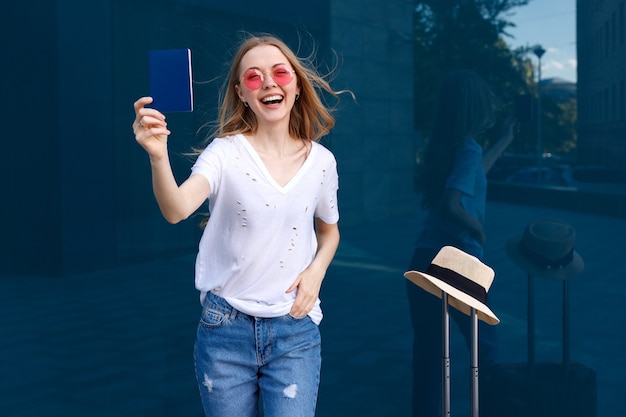 Happy woman with passport and luggage on a blue background