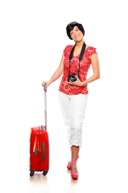 a happy woman with a red suitcase and camera going on holidays