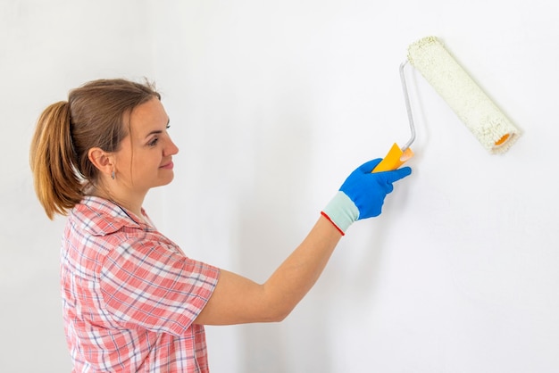 Happy woman with roller painting wall in her new apartment