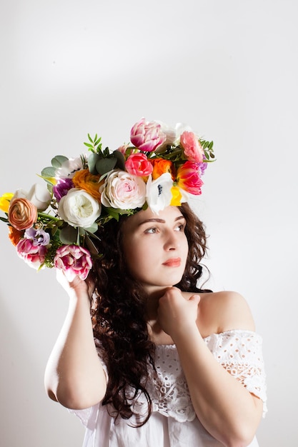 Happy woman with wreath of flowers looking aside isolated on a white background