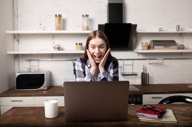 Happy woman working at home in the morning. Girl drinking coffee. She is using her laptop