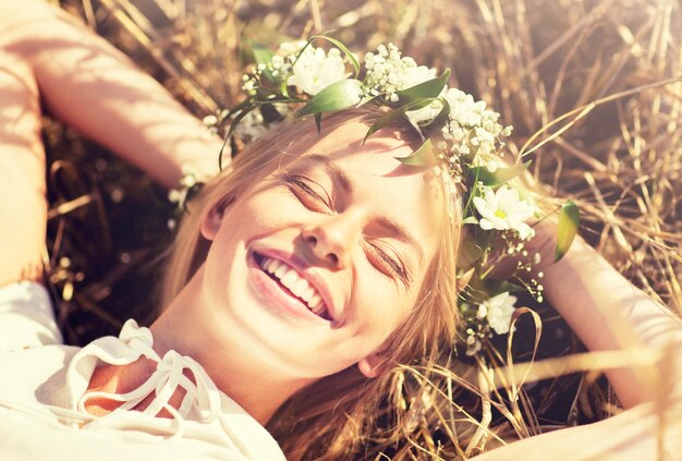 Photo happy woman in wreath of flowers lying on straw