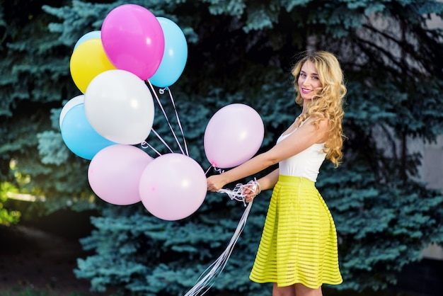 Happy woman in yellow dress with colorful balloons