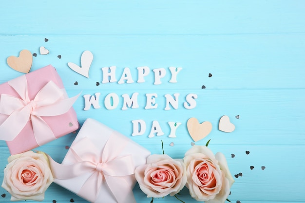 Happy Women's Day text with roses, hearts and gifts on blue background