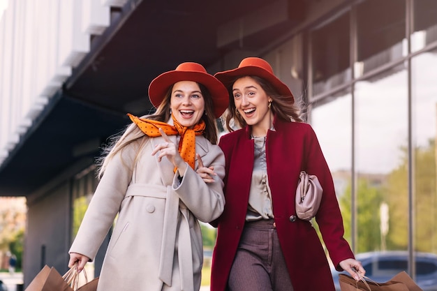 Happy women with shopping bags pointing finger in the shop