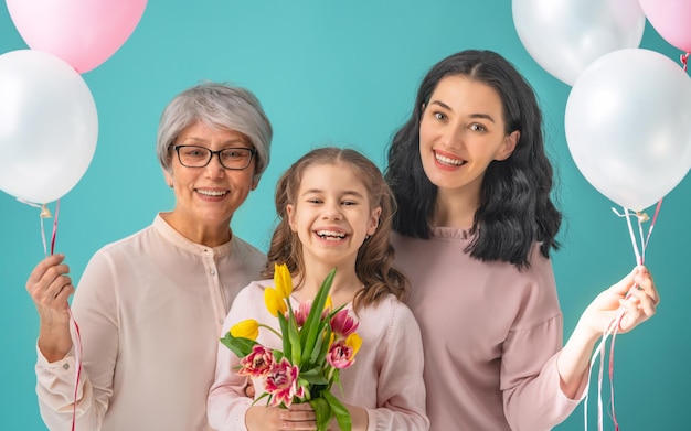 Happy womens day Child daughter is congratulating mom and grandma giving them yellow flowers tulips