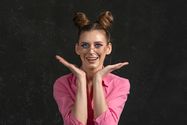 Happy wondering young woman with blue pink shadows on black background Portrait of girl in big glasses