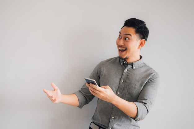 Happy and wow face of Asian man use smartphone on isolated gray background.