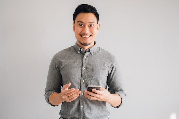 Happy and wow face of Asian man use smartphone on isolated gray background.