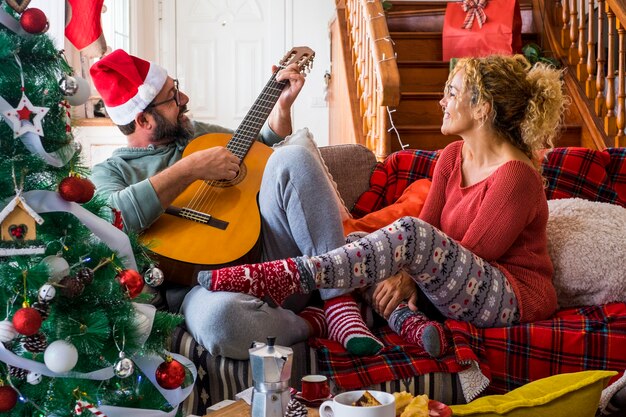 Happy young adult couple at home enjoy and celebrate christmas eve together having fun and love