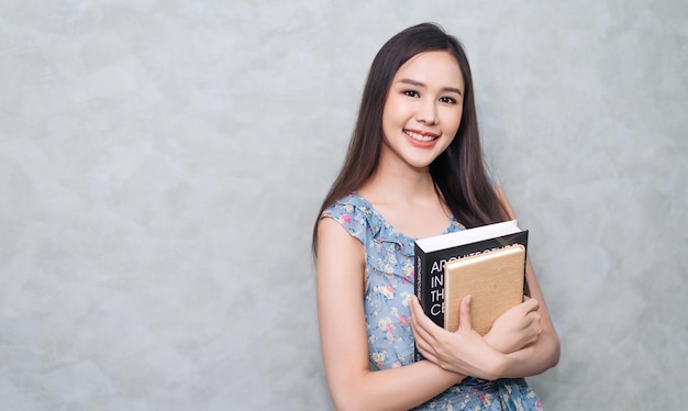 Happy young adult woman holding textbook in education concept