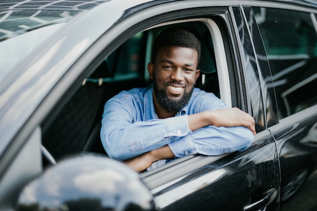 Happy young african american man driving a car