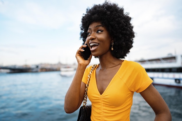 Happy young african american young woman talking with cellphone in city