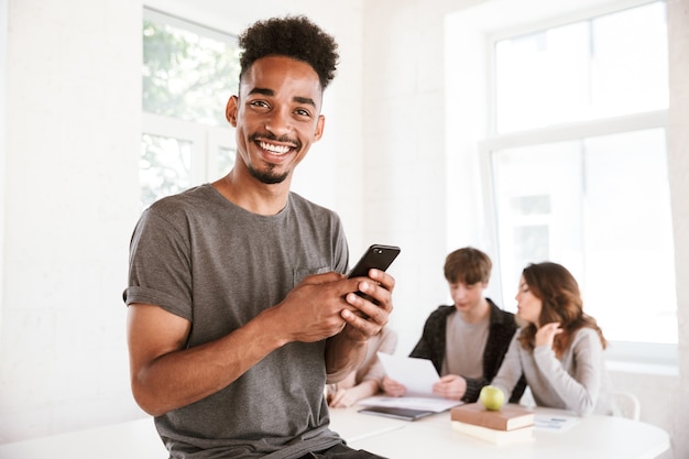 Happy young african guy chatting by mobile phone