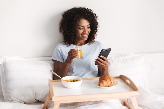 Happy young african woman using mobile phone