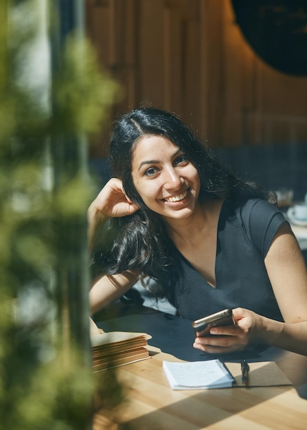 Happy young Arab woman talking on the phone at the cafe